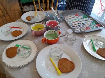 A picture of biscuits with bowls of coloured icing and decorations